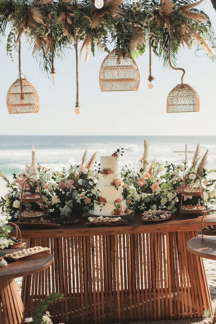 mesa de madeira com bolo e muitas flores arranjo de flores e lustres pendurados