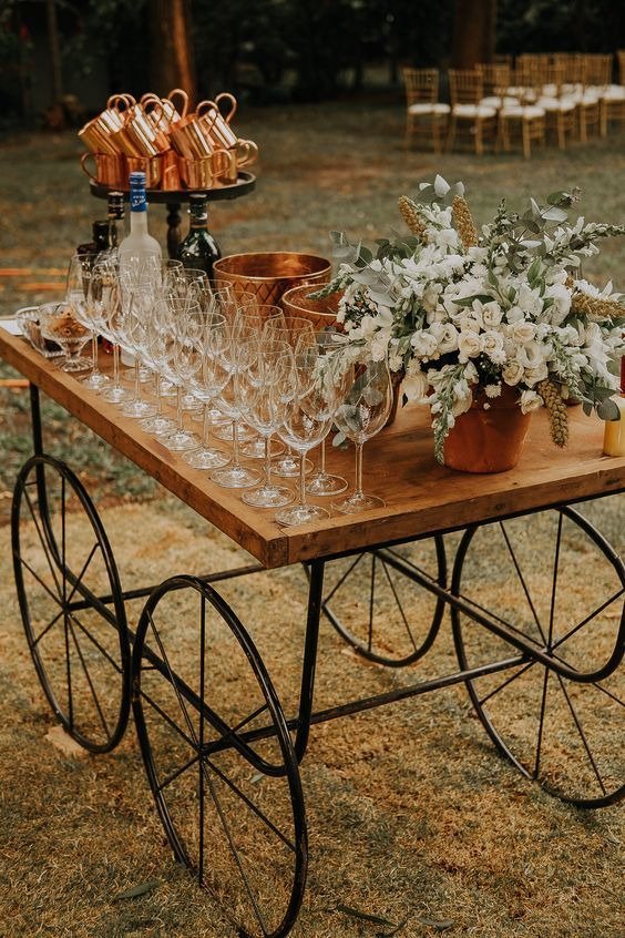 mesa de madeira com rodas de metal com tacas e bebidas em cima