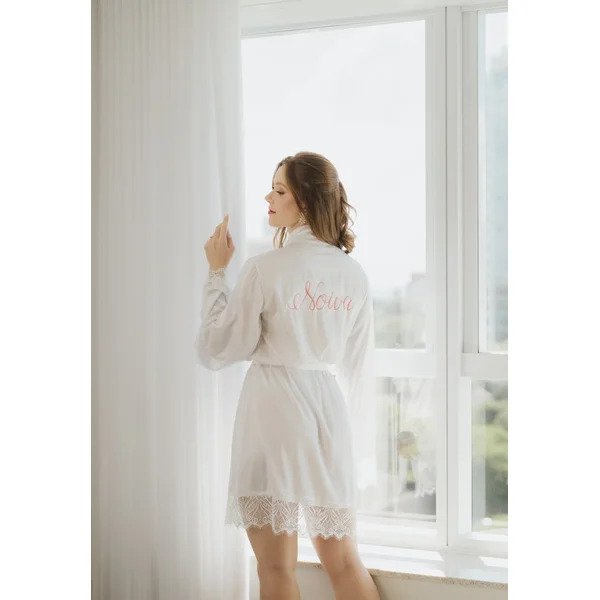 mulher perto da cortina de costas com robe bordado noiva em rosa na parte de tras