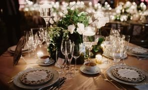 mesa de convidados em casamento com pratos talheres tacas velas e flores brancas