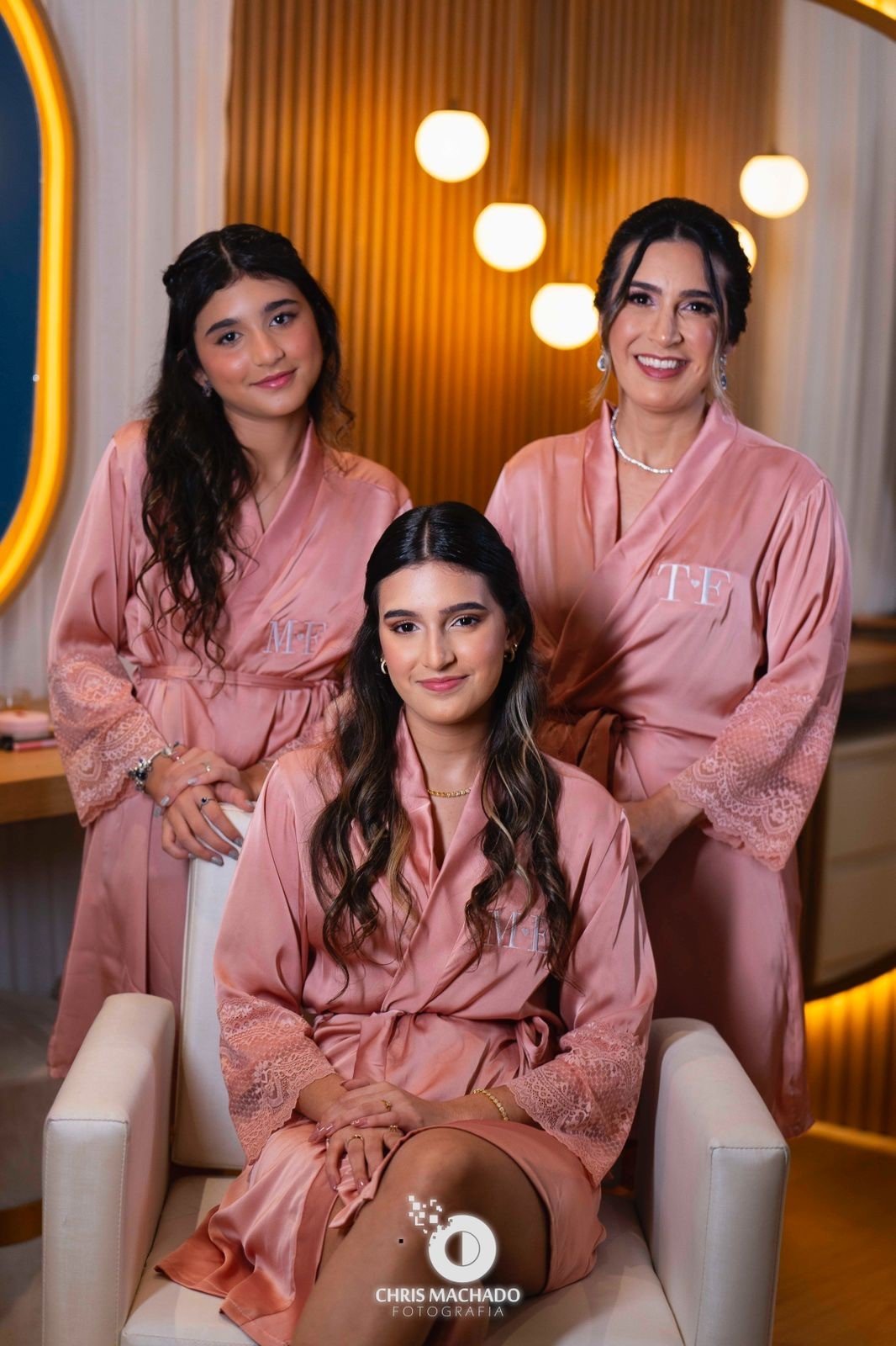 debutante sentada com mae e irma atras todas com robe rosa com guipir nas mangas