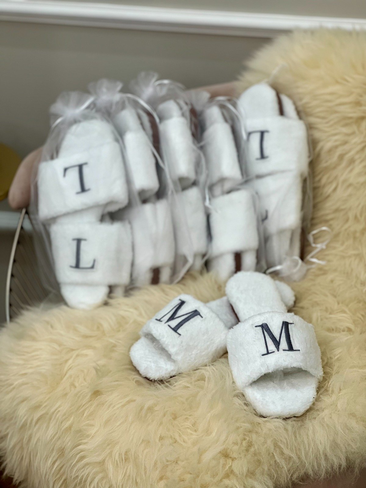 pantufas brancas com as iniciais l e m sobre tapete bege