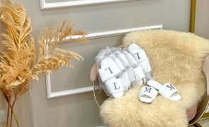 pantufas brancas com as iniciais l e m sobre tapete na cadeira pantufas brancas com as iniciais l e m sobre tapete na cadeira