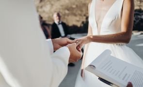 esposo colocando anel em dedo da esposa os dois estao de branco