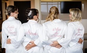 quatro mulheres de costas com robe branco e bordado rosa noiva mae da noiva e duas com irma da noiva