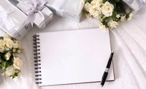 caderno com folha em branco e caneta sobre com presentes e flores em volta