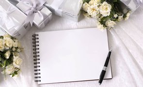 caderno com folha em branco e caneta sobre com presentes e flores em volta
