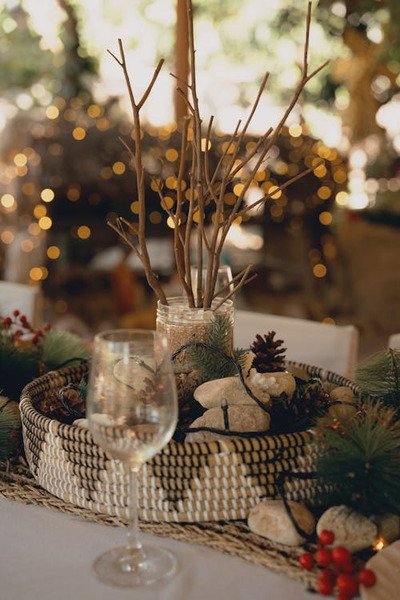 cesto tramado com pedras pote com areia e galhos dentro sobre a mesa