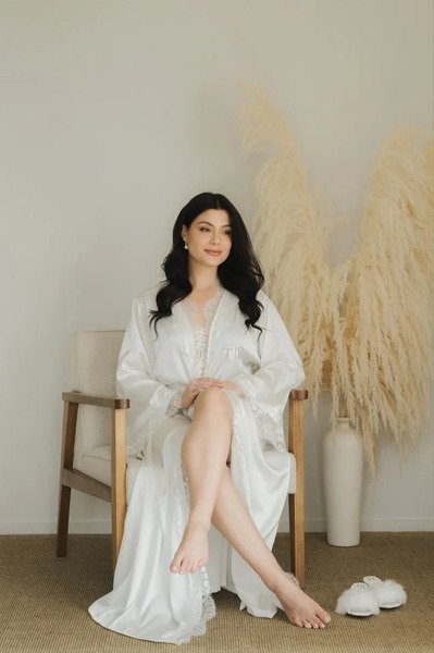 modelo sentada olhando para o lado usando robe longo personalizado para noivas com renda chantilly robe longo yasmim