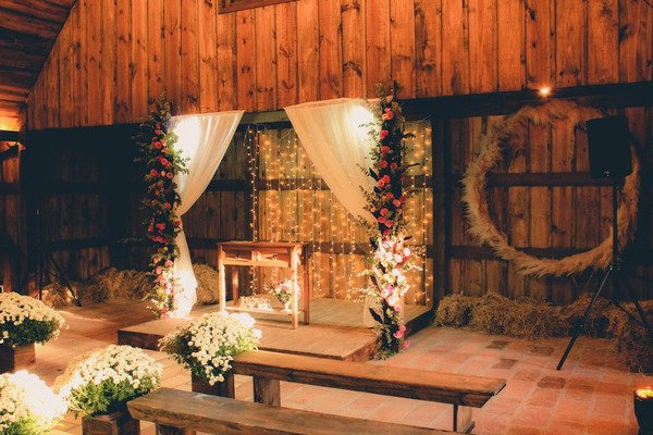 altar com pano branco e flores em salao de madeira com bancos de madeira e flores brancas do lado