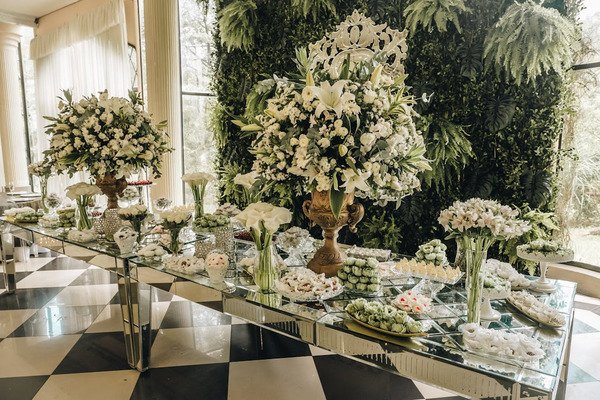 mesa espelhada com vasos de flor e doces