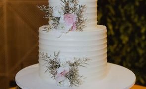 bolo de casamento branco de dois andares com flores rosa claro em bandeja prata