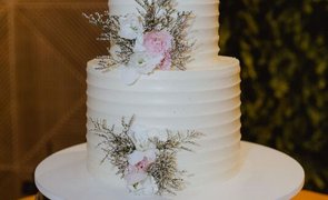 bolo de casamento branco de dois andares com flores rosa claro em bandeja prata