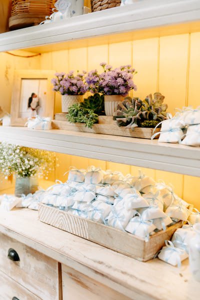 bem casados azul claro sobre balcao com flores roxa e fotos do casal