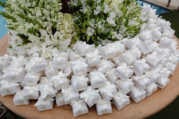 mesa redonda de madeira com bem casados brancos com flores brancas junto