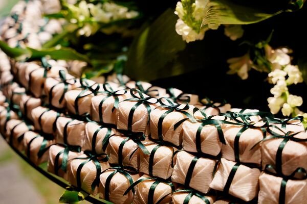 bem casados beje com fita verde escura sobre mesa rdonda com flores