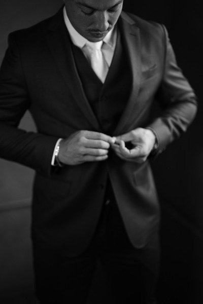 foto em preto e branco de noivo fechando botao do terno
