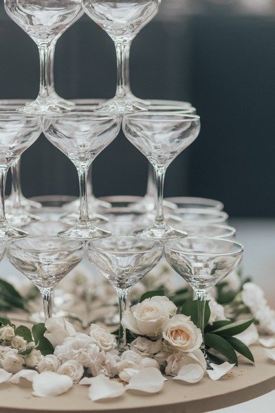 foco em torre de tacas de champanhe com rosas brancas sobre a mesa