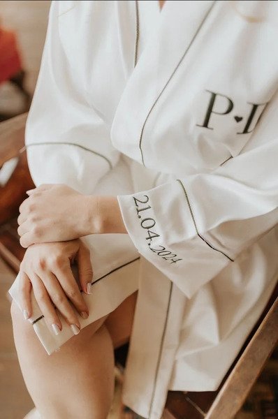 modelo sentada com pernas cruzadas usando robe personalizado com bordados para noivas robe isabela