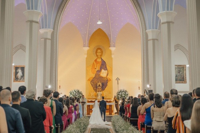imagem de casamento dentro da igreja convidados em pe e noivos no altar