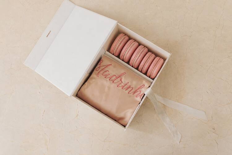 caixa branca aberta com robe rose com escrito madrinha em rosa e cinco macarons rosas
