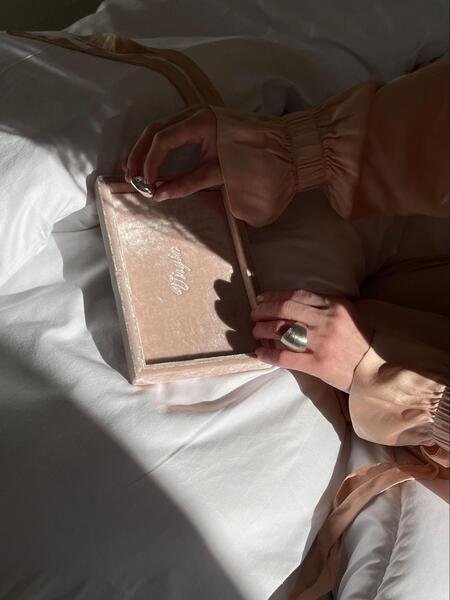 maos femininas ajustando joia sobre porta joia rose sobre a cama