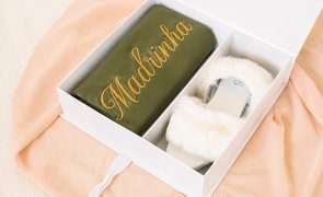 caixa branca aberta com duas divisorias uma com robe verde com escrito madrinha em dourado e pantufa raterinha branca com plumas na outra caixa branca aberta com duas divisorias uma com robe verde com escrito madrinha em dourado e pantufa raterinha branca com plumas na outra