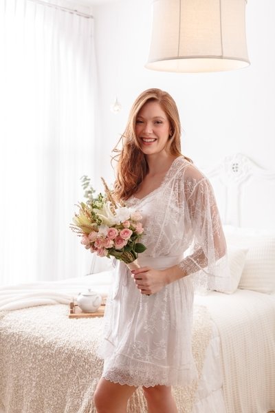 modelo segurando buque com flores rosas e brancas usando robe de renda chantilly branco